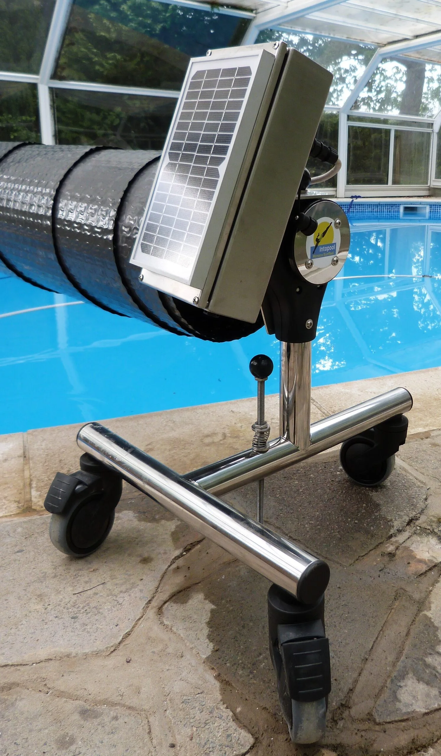 Solar powered pool cover reel, black cover on silver stand with wheels.