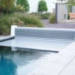 Gray automatic pool cover with aluminum slats, protecting the water.