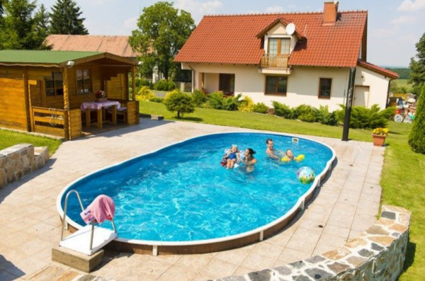 A blu-line swimming pool in a garden with kids and adults playing in the pool.